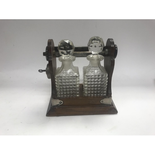 961 - Two small tantalus decanters bottles with in a lockable cradle.