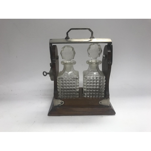 961 - Two small tantalus decanters bottles with in a lockable cradle.