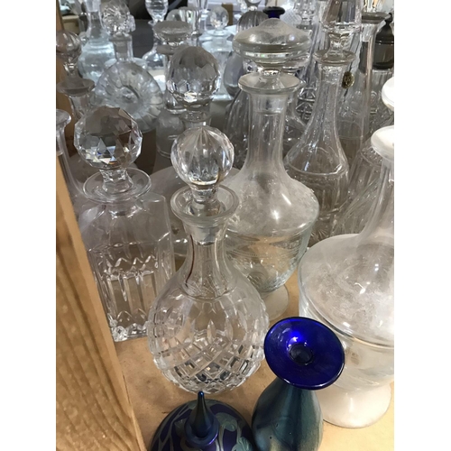 975 - A large collection of decanters including some cut glass and alum bay and okra examples.