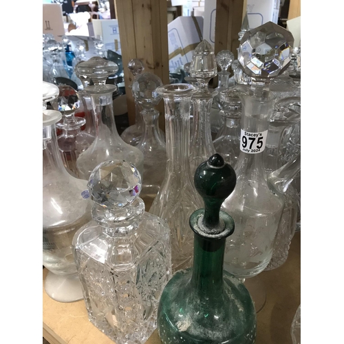 975 - A large collection of decanters including some cut glass and alum bay and okra examples.