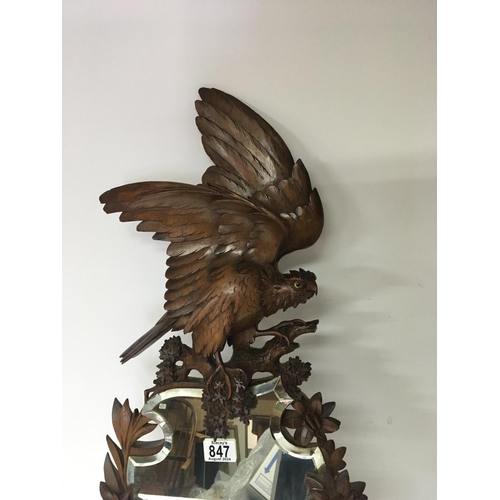 847 - A Quality Black Forest carved wood mirror the top with a bird of prey with glass eyes with a shaped ... 