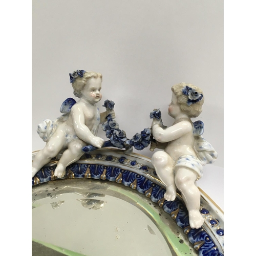 1135 - A Dresden Porcelain oval mirror with raised cherubs flowers and foliage. 33 cm .