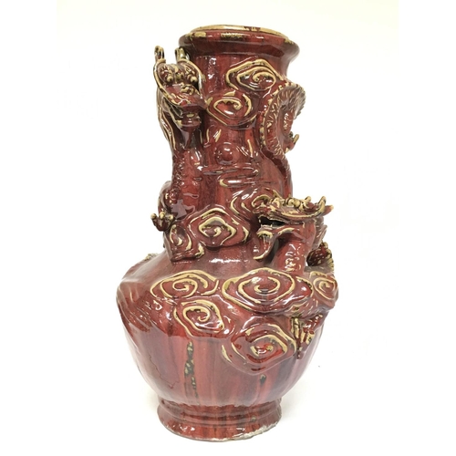 822 - A large Chinese Sang De Boeuf Vase with relief dragons and cloud decoration, 56cm tall. This lot can... 