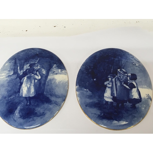 968 - A pair of quality Doulton Burslem blue and white oval wall plaques decorated with figures of young c... 