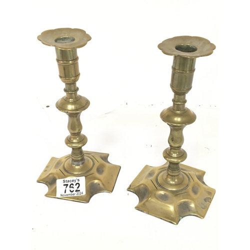 762 - A pair of 18th Century brass candle sticks. With shaped stems and bases with visible seem. Height 20... 