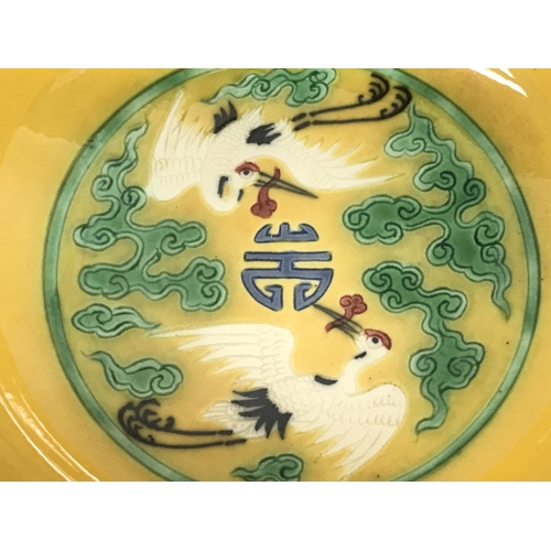 828 - A Chinese yellow glaze bowl with decoration of cranes. 15cm wide. This lot cannot be posted