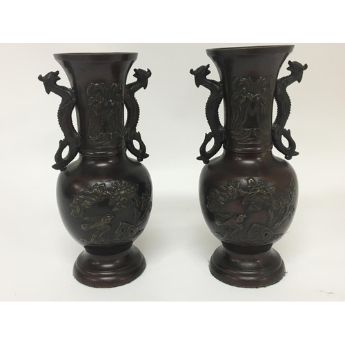 857 - A pair of Japanese late 19th century vases with raised decoration and side handles in the form of dr... 