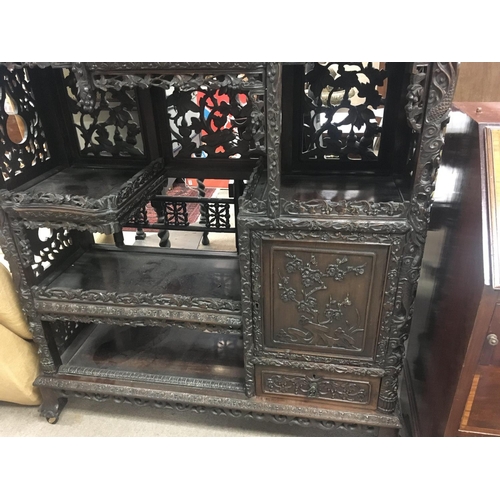 1317 - A Chinese display cabinet profusely carved with open sections single cupboard door and drawer on bal... 