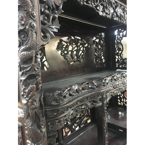 1317 - A Chinese display cabinet profusely carved with open sections single cupboard door and drawer on bal... 