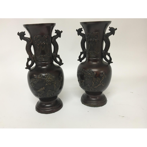 918 - A pair of Japanese late 19th century vases with raised decoration and side handles in the form of dr... 