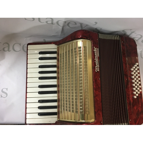 167 - Piano accordion by Worldmaster Foreign. Red, white and gold and is roughly 46 cm wide and 18cm tall.