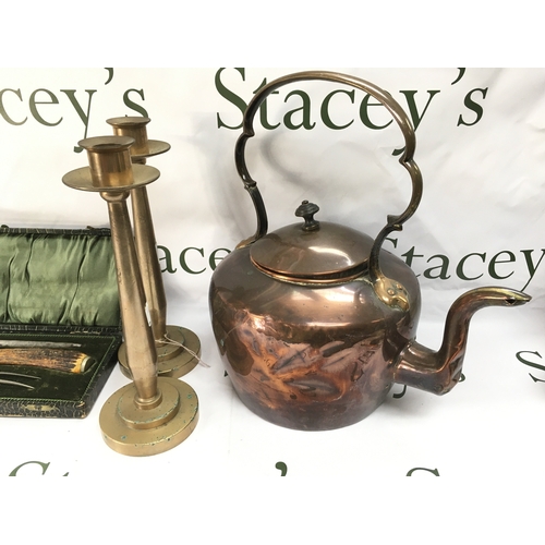 88 - A copper kettle pair of heavy candlestick holders and a cased carving set.