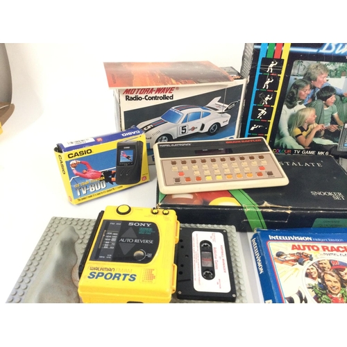 711 - A box containing a Mattel Intellivision plus 6 games, also a Mattel Brain Baffler, a Sony Walkman Sp... 