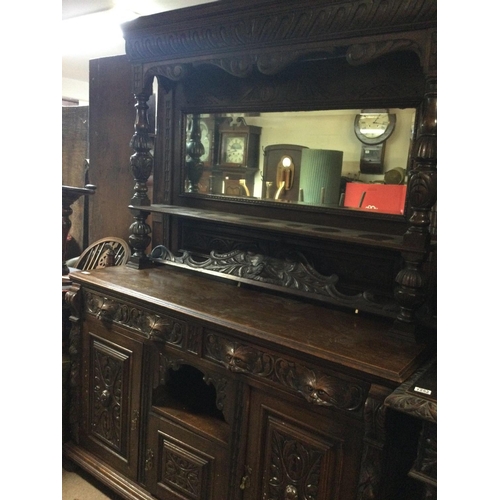 1253 - A oak mirror back sideboard the raised back above two drawers and cupboards under on ball shaped fee... 