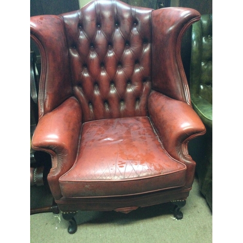 1255 - A red leather wing armchair with button back on cabriole legs .