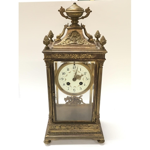 1312 - A French early 20th century gilt metal ornate clock with stylised dolphins, urn top, a ceramic dial ... 