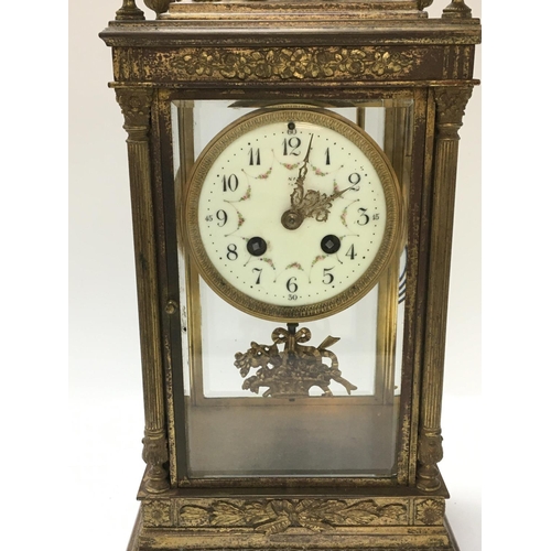 1312 - A French early 20th century gilt metal ornate clock with stylised dolphins, urn top, a ceramic dial ... 