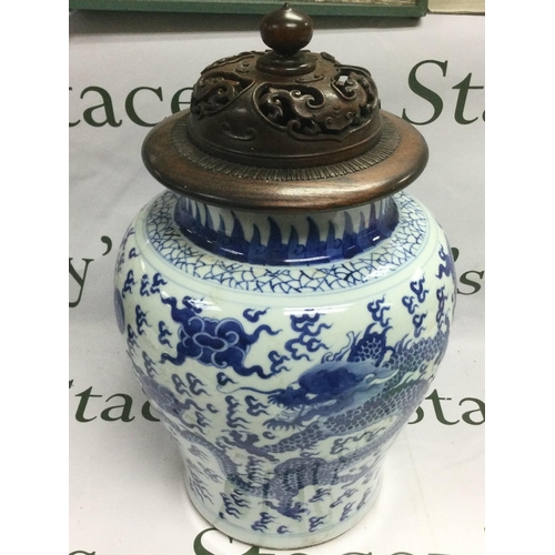 906 - A blue and white lidded vase depicting a dragon chasing a pearl, the hardwood lid having carved pier... 