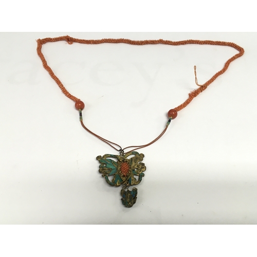 819 - A coral necklace with a butterfly style brass pendant. NO RESERVE