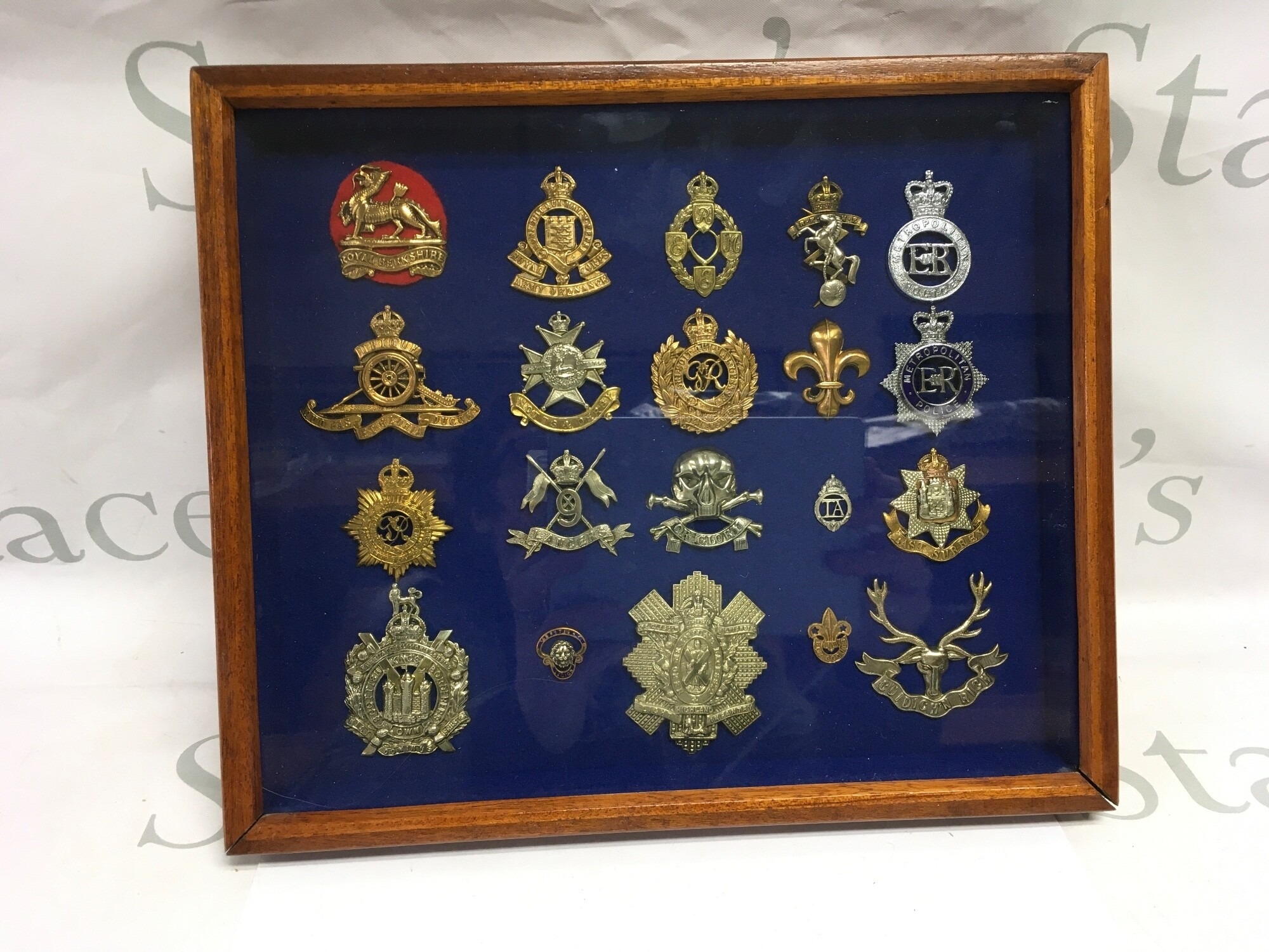 A framed and glazed collection of cap badges.