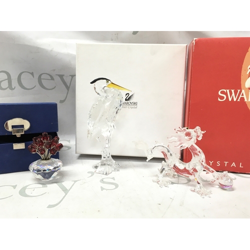 1021 - Boxed Swarovski crystal glass figures including silver heron, crystal vase of red roses, dragon (eye... 