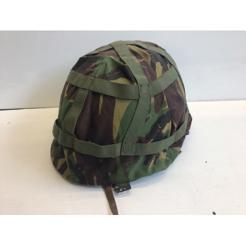 655 - An American Combat helmet with camouflage cover. Vietnam era.