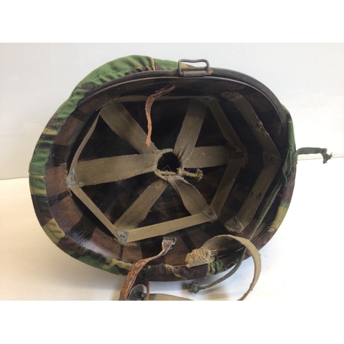 655 - An American Combat helmet with camouflage cover. Vietnam era.