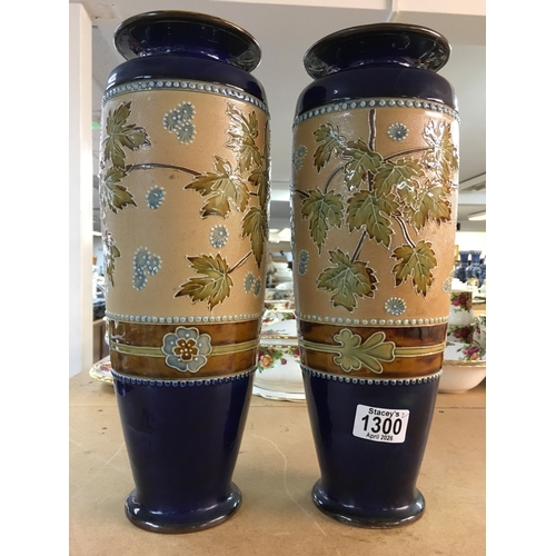 1300 - A pair Royal Doulton Lambeth Stoneware vases. 36cm in height. Decorated In flowers and foliage.