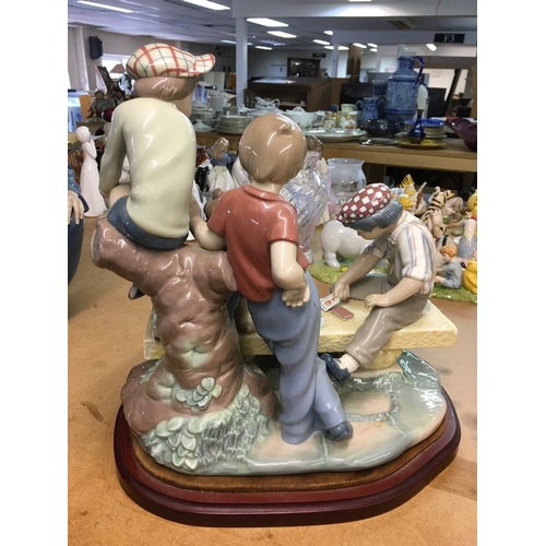 1281 - A large Lladro figure group of young boys playing cards on a bench. 30cm in height, not including wo... 