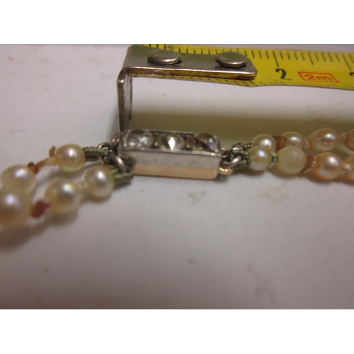 80 - Double strand pearl necklace with unmarked white and yellow gold clasp set with three diamonds