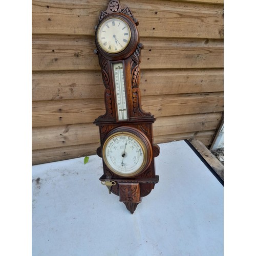 72 - Early 20th century carved oak case barometer with thermometer and clock by Harrop of Manchester