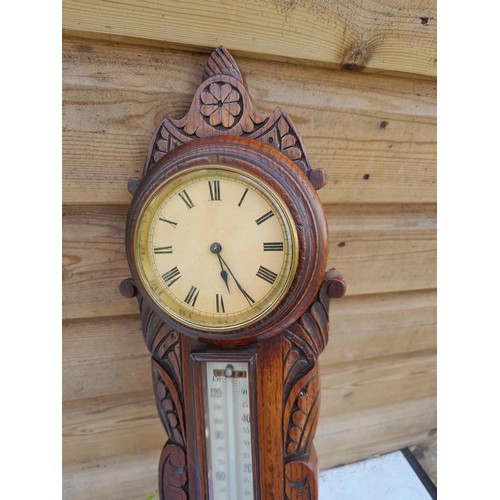 72 - Early 20th century carved oak case barometer with thermometer and clock by Harrop of Manchester