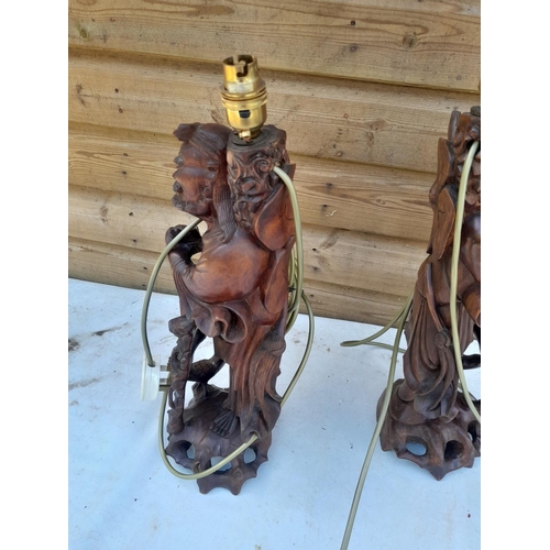 623 - Pair of late 19th century Chinese carved hardwood immortals with glass teeth, later adapted to lamps