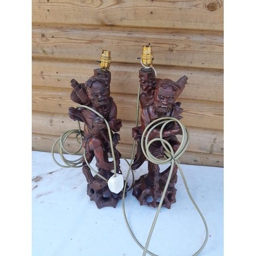 623 - Pair of late 19th century Chinese carved hardwood immortals with glass teeth, later adapted to lamps