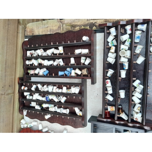 131 - Collection of porcelain and base metal thimbles in hanging racks