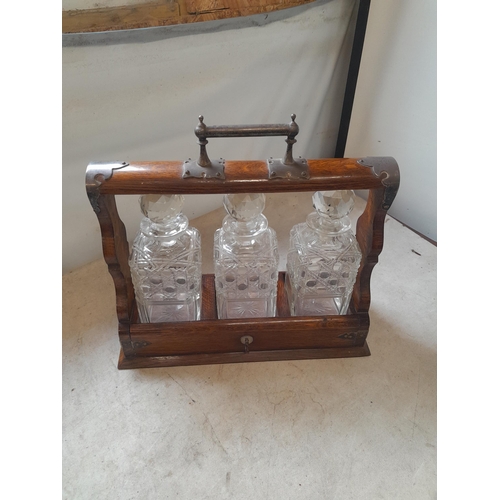 56 - Edwardian oak three bottle tantalus with silver plated mounts and  key