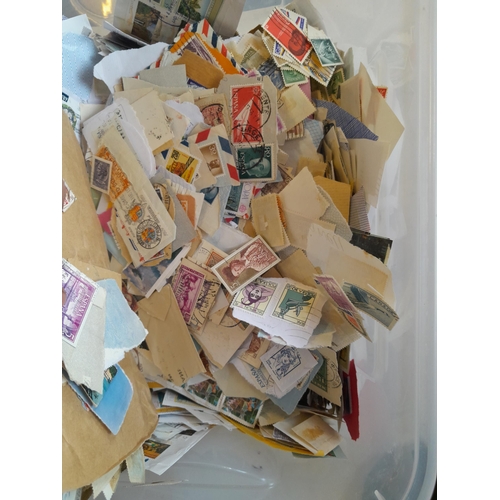 142 - Plastic container of mixed world stamps, on and off paper, good rummagers lot