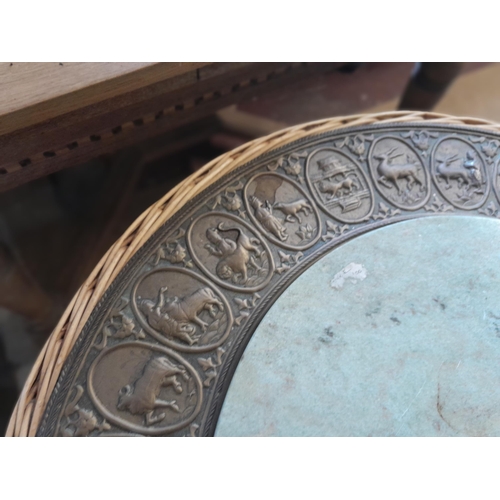 49 - An interesting vintage Indian wicker table with hardstone panel and repouse work brass relief of pan... 