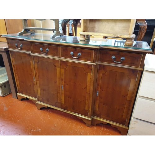 581 - Yew Breakfront Sideboard with Three Drawers, Four Cupboards and Glass Top Overlay.