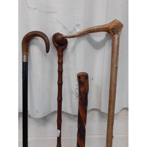 217 - Four Wooden Walking Sticks - Two have bone handles, one depicts hand holding a globe and one twisted... 