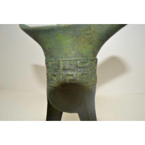 149 - A CHINESE BRONZE 'JUE' CUP, Shang type on tripod supports, single side handle, decoratively banded, ... 