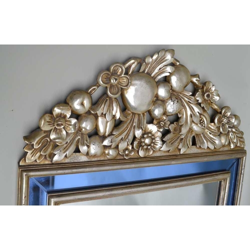 262 - A 20TH CENTURY WALL MIRROR, carved and silvered finish frame with fruit & floral crest, the frame in... 