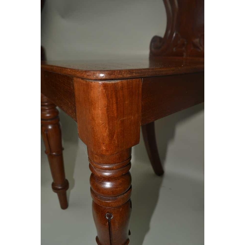 304 - A PAIR OF WILLIAM IV PERIOD MAHOGANY HALL CHAIRS with fancy shaped and carved backs, and solid seats... 