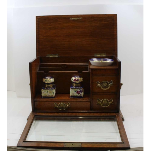 308 - AN EDWARDIAN OAK WRITING CABINET with drop fronted glass panel, revealing drawers and two inkwells, ... 