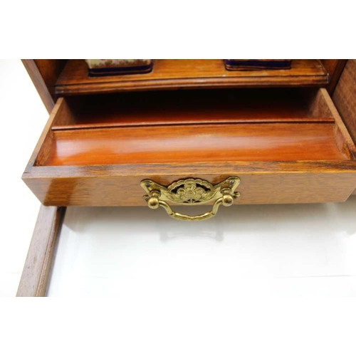 308 - AN EDWARDIAN OAK WRITING CABINET with drop fronted glass panel, revealing drawers and two inkwells, ... 