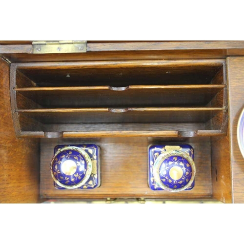 308 - AN EDWARDIAN OAK WRITING CABINET with drop fronted glass panel, revealing drawers and two inkwells, ... 