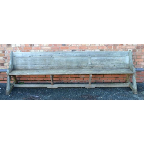 320 - A LATE 19TH CENTURY WEATHERED PINE LONG PEW, having shelf back, shaped ends, and plank seat, 315cm w... 