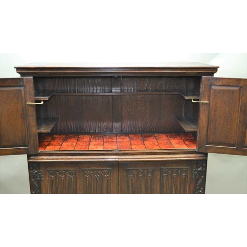 261 - A 20TH CENTURY OAK COCKTAIL CABINET, in the 17th century style, with linen fold and blind fret decor... 