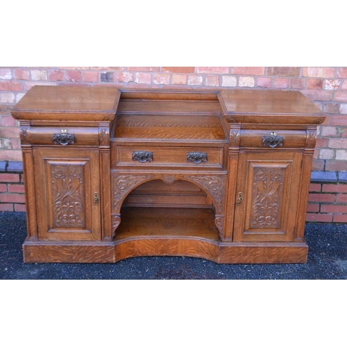 321 - AN ART NOUVEAU DESIGN OAK SIDEBOARD, tiwn pedestal design, with carved panel decoration, fitter thre... 