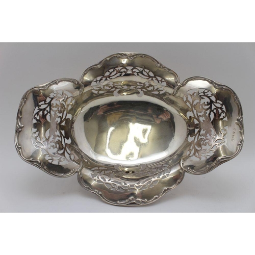 10 - An early 20th century silver bread basket, shaped rim, pierced decoration, of oval form, raised on f... 